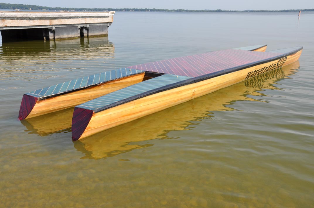 image of a hand built wood paddleboard with pontoons and a deck.