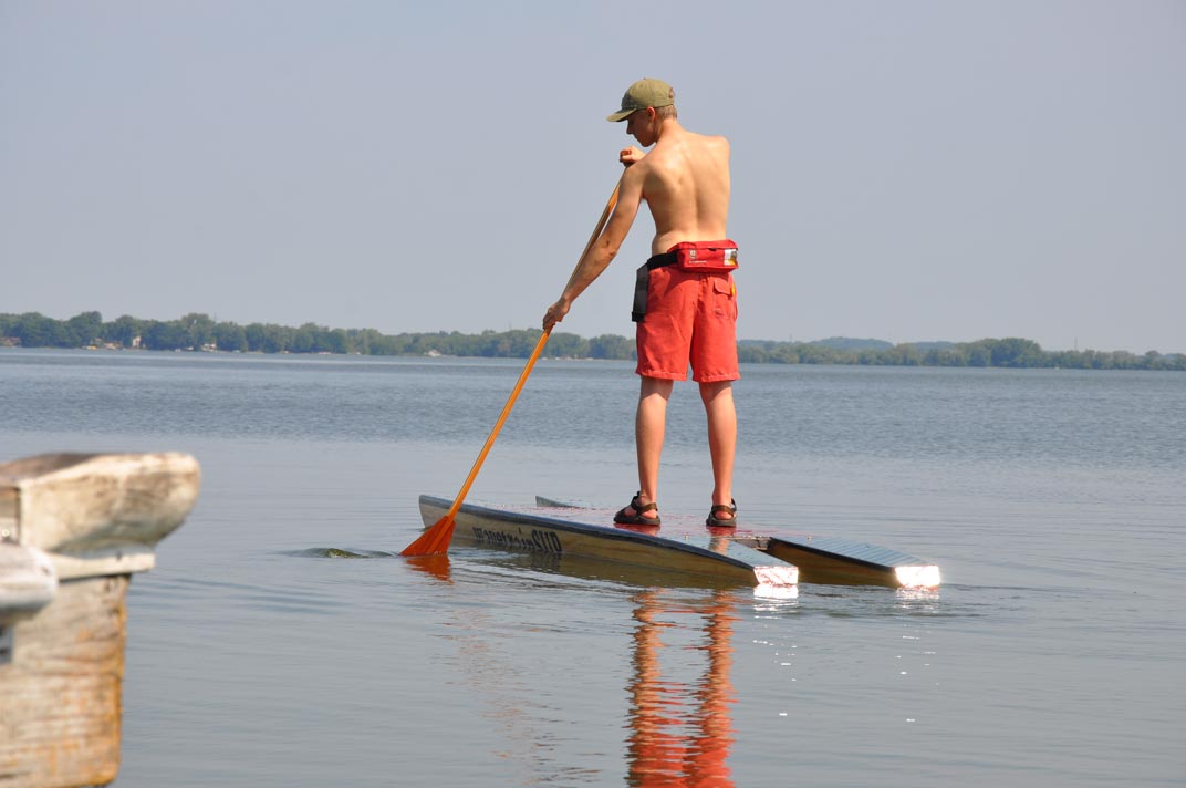 picture of a paddleboard featuring two pontoons and a deck.